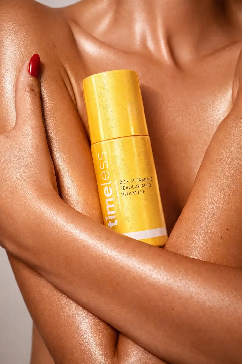 Yellow vitamin C skincare bottle held against warm, reflective skin